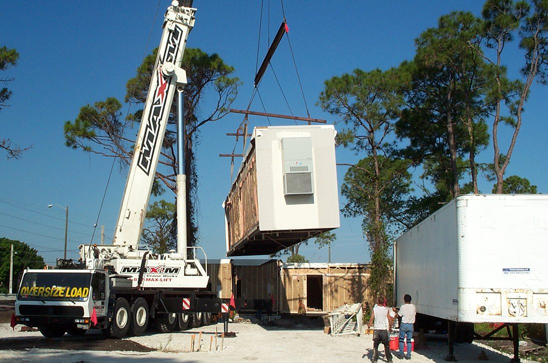 A crane lowering a modular building into place.