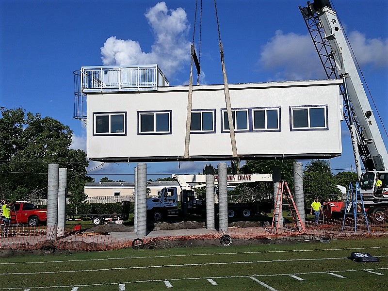 Modular pressbox moved into place with crane